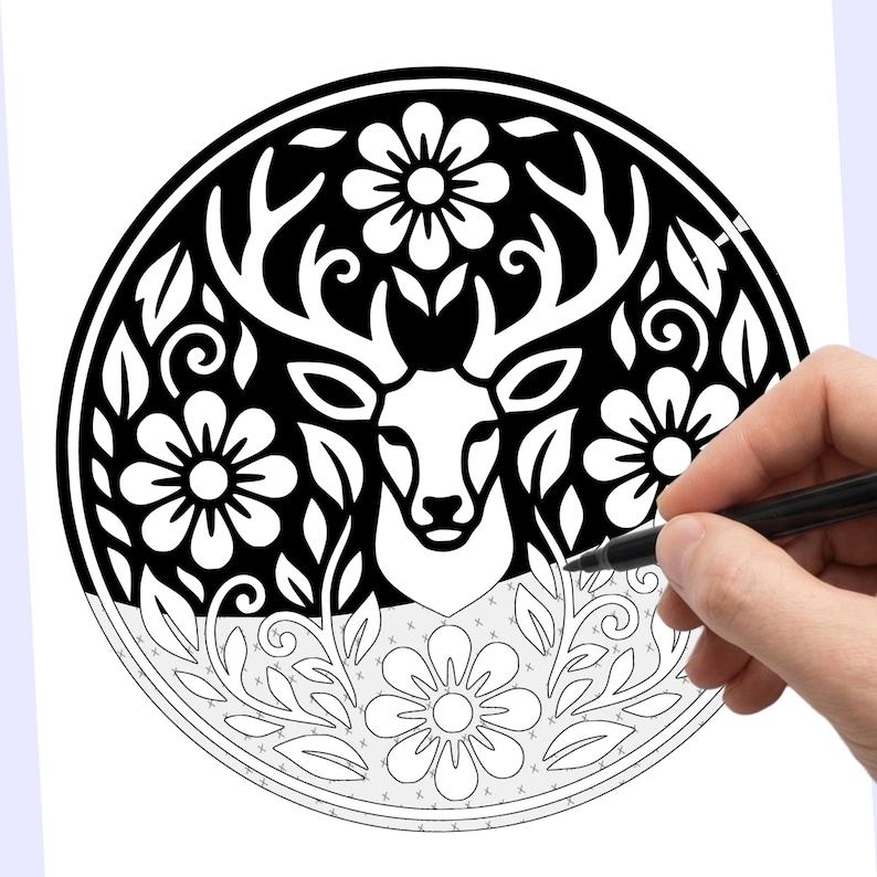 May include: Black and white deer and floral design. The image features a detailed illustration of a deer head with large antlers, surrounded by flowers and leaves. The design is circular and is being colored with a black pen.