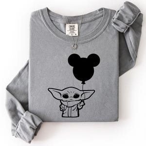 A gray long-sleeved t-shirt with a graphic design featuring a cartoon character holding a balloon.