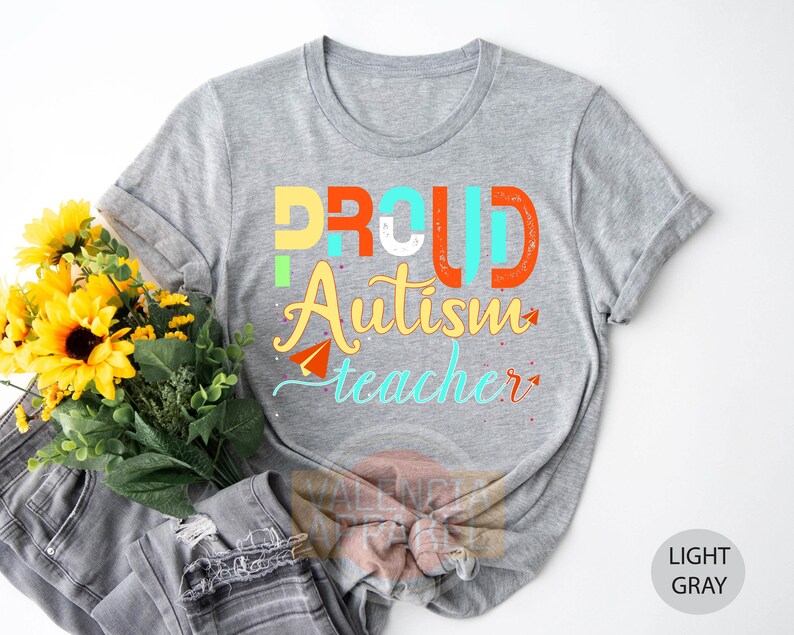 a t - shirt that says proud autism teacher next to a bouquet of sunflower