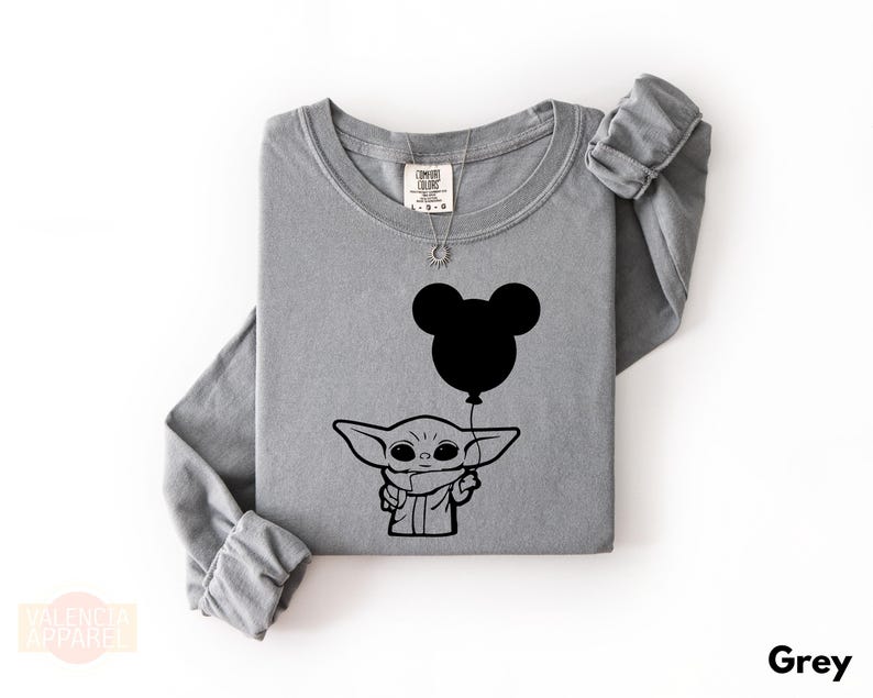 A gray long-sleeved t-shirt with a graphic design featuring a cartoon character holding a balloon.