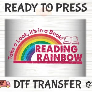 May include: A DTF transfer design with the text "READY TO PRESS" at the top. The design features a rainbow arch with the words "Take a Look, it's in a Book!" and "READING RAINBOW". An open book graphic is also included.