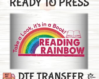 May include: A DTF transfer design with the text "READY TO PRESS" at the top. The design features a rainbow arch with the words "Take a Look, it's in a Book!" and "READING RAINBOW". An open book graphic is also included.