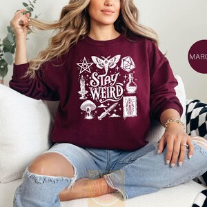 a woman sitting on a couch wearing a maroon sweatshirt