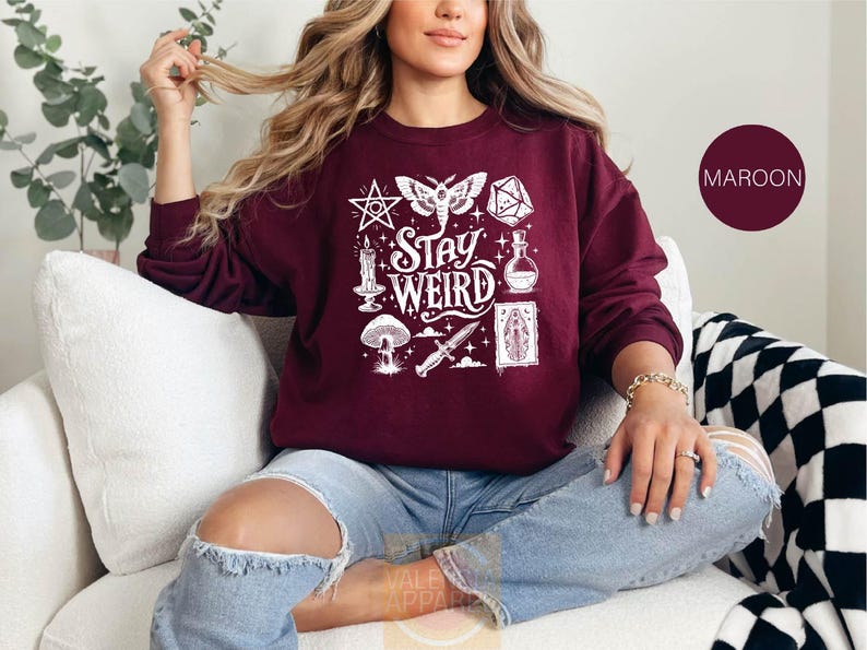 a woman sitting on a couch wearing a maroon sweatshirt