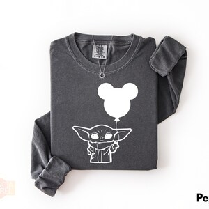 A gray long-sleeved t-shirt with a white graphic design depicting a cartoon character holding a balloon.