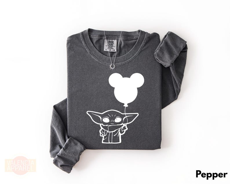 A gray long-sleeved t-shirt with a white graphic design depicting a cartoon character holding a balloon.
