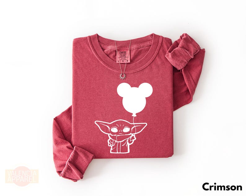 A red long-sleeved t-shirt with a white graphic design depicting a cartoon character holding a balloon.