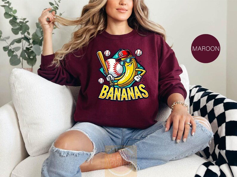 a woman sitting on a couch wearing a maroon sweatshirt
