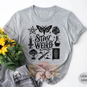 a t - shirt with the words stay weird on it