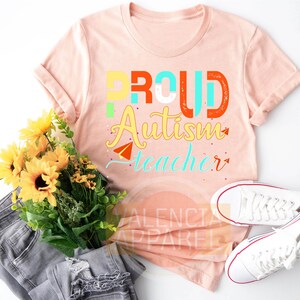 a t - shirt that says proud autism teacher next to a bouquet of sunflower