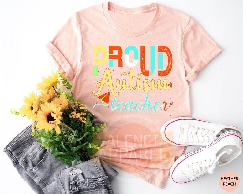 a t - shirt that says proud autism teacher next to a bouquet of sunflower