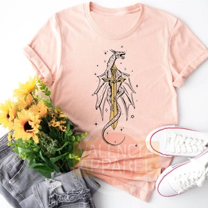 a t - shirt with a dragon on it next to a bouquet of sunflower