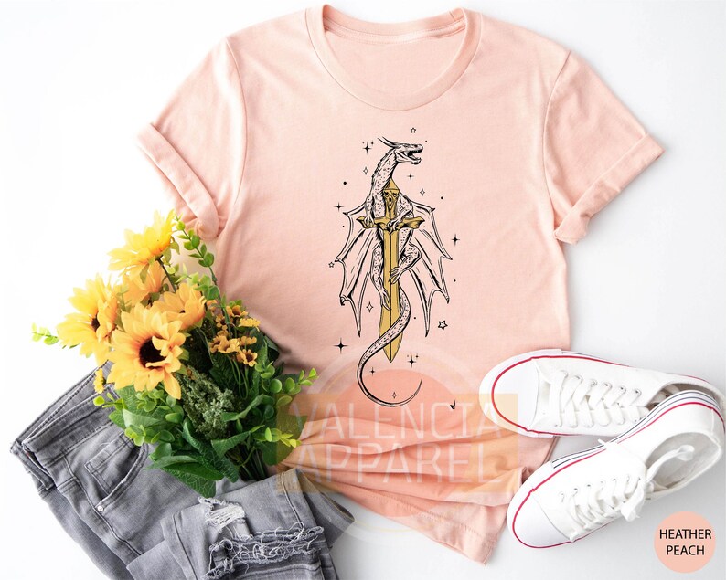 a t - shirt with a dragon on it next to a bouquet of sunflower