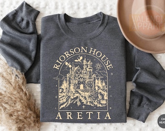 May include: Dark heather grey sweatshirt with a gold graphic of a castle with the text "RIORSON HOUSE ARETIA".