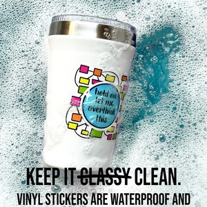 May include: A white stainless steel tumbler with a colorful vinyl sticker that says "hold on let me overthink this". The tumbler is submerged in soapy water, demonstrating that the sticker is waterproof and dishwasher safe.