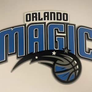 May include: A blue and gray Orlando Magic logo with a basketball and a star. The logo is on a white background.