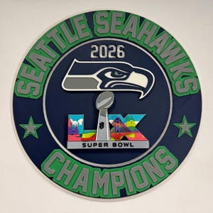 May include: A round, navy blue Seattle Seahawks Champions sign with green and gray lettering. The sign features the Seahawks logo, the Super Bowl trophy, and the text "2026" and "Super Bowl LX". Two green stars flank the trophy.