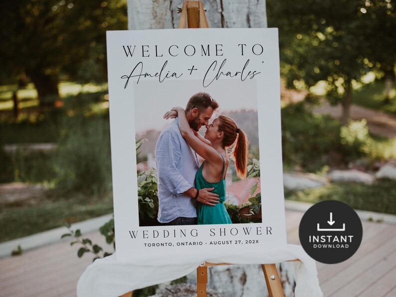 May include: A white wedding sign on an easel with the text "WELCOME TO Amelia + Charles" above a photo of a couple embracing. Below the photo, it reads "WEDDING SHOWER, TORONTO, ONTARIO, AUGUST 27, 202X." A black circle with "INSTANT DOWNLOAD" is in the bottom right.