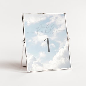 May include: A silver table number holder with a cloudy sky background. The number "1" is displayed in gray text with the word "table" written in cursive above it.