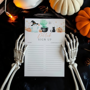 May include: A Halloween-themed sign-up sheet with the words "Potluck Sign Up" in gold script. The sheet is held by two skeleton hands and features illustrations of pumpkins, a ghost, and a black cat. Pumpkins and gourds are in the background.