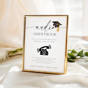 May include: A gold-framed sign featuring the text audio GUESTBOOK with a graduation cap icon. It includes instructions to pick up the phone and leave a message after the tone, plus the name Jasmine Carcamo and Class of 202X at the bottom.