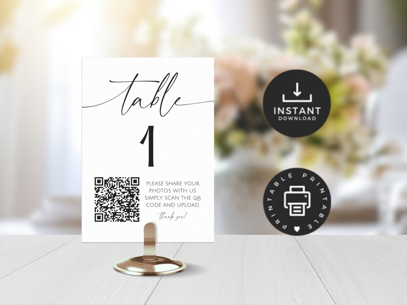 May include: A white table number card with black calligraphy that reads "table 1". A black and white QR code is printed below the table number with the text "Please share your photos with us simply scan the QR code and upload. Thank you!"