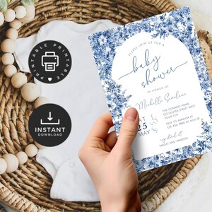 May include: Printable baby shower invitation with a blue floral design. The invitation features the text "Please join us for a baby shower" and "In honor of Michelle Giulane". The date and time of the shower are listed as "At 2:00 PM May 25th". The location is listed as "The Conrod Home 123 Center Street West Your City". The RSVP information is listed as "RSVP to Amanda at 123-456-7890 by Nov 18". The invitation also includes the text "Registered at Target and Amazon".