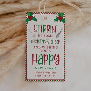 Könnte beinhalten: Ein weißer Geschenkanhänger mit roten und grünen Streifen. Der Anhänger trägt eine festliche Botschaft, die lautet "Stirrin' up some Christmas cheer and wishing you a Happy New Year!!" mit einem Weihnachtssterndesign und Küchenutensilien. Der Anhänger enthält auch den Text "Season's Greetings from the Smith's".