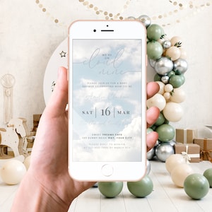 May include: A baby shower invitation displayed on a smartphone screen, featuring a blue sky and white clouds backdrop. The text reads "We're on cloud nine" and includes the date "Sat 16 Mar" and the location "Sweet Dreams Cafe, 123 Sunny Skies Way, Your City".