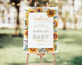May include: A white welcome sign with a sunflower border. The sign reads "A little sunflower is on their way. Welcome to Jessica's Baby Shower 05.18.202X"