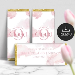 May include: Pink and gold baby shower favour chocolate bar wrappers with the text "We are on Cloud 9" and "Thank you for joining us at Jennifer's Baby Shower August 19, 2023".