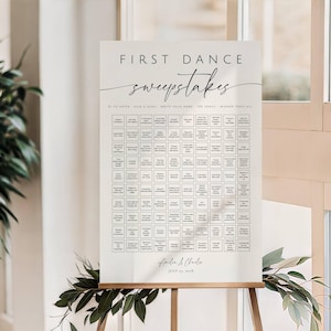May include: A white rectangular sign titled FIRST DANCE sweepstakes in black text. It features a grid of small squares for song entries, with the names Amelia & Charles and the date JULY 15, 2025, printed at the bottom in a script font.