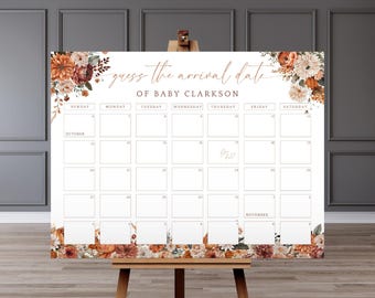 May include: A white calendar with the text "guess the arrival date of BABY CLARKSON" in gold script. The calendar has a floral design in shades of orange, brown, and burgundy. The calendar is displayed on a wooden easel.