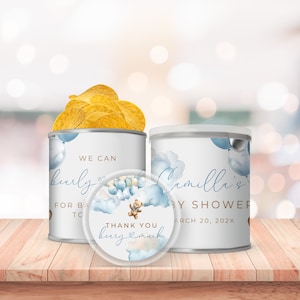 May include: Two blue and white favor cans with a teddy bear and balloons design. The text on the cans reads "We can barely wait" and "Camille's Baby Shower March 20, 202X". A round sticker with a teddy bear and balloons design reads "Thank you very much".