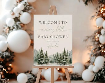 Könnte beinhalten: Ein rechteckiges Willkommensschild auf einer Holzstaffelei mit dem Text "WELCOME TO a merry little BABY SHOWER IN HONOR OF MOM-TO-BE Amelia" über einer Aquarellillustration eines grünen Kiefernwaldes mit verschneiten Bäumen.