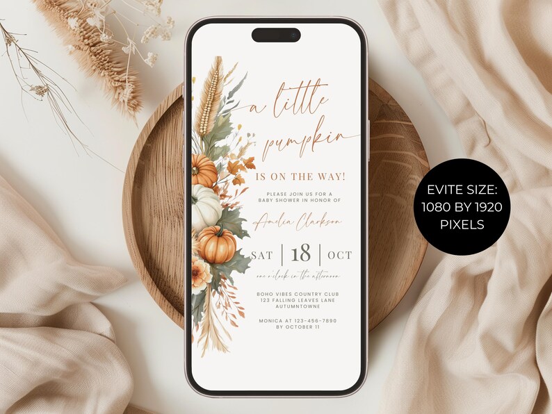May include: A smartphone displaying a digital baby shower invitation with the text A little pumpkin IS ON THE WAY! The design features watercolor illustrations of orange and white pumpkins, dried grasses, and autumn leaves on a white background.