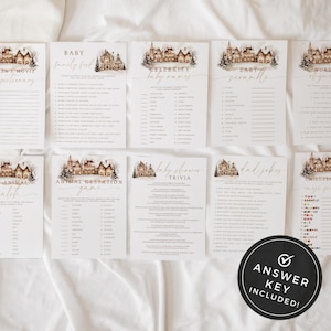 May include: A collection of baby shower game cards with a winter village illustration. Games include trivia, baby names, and nursery rhymes. An answer key is included. The cards are arranged on a white surface.