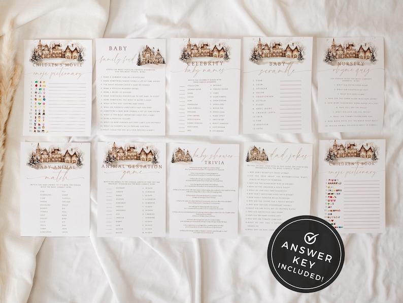 May include: A collection of baby shower game cards with a winter village illustration. Games include trivia, baby names, and nursery rhymes. An answer key is included. The cards are arranged on a white surface.