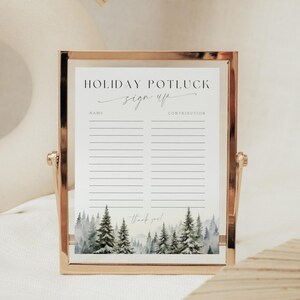 May include: A gold-framed sign with a white background and black text that reads "Holiday Potluck Sign Up". The sign has two columns labeled "Name" and "Contribution". The bottom of the sign features a watercolor illustration of a snowy forest.