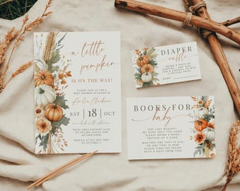 May include: A baby shower invitation set featuring a large invitation, a diaper raffle card, and a books for baby card. The stationery has a cream background with watercolor illustrations of pumpkins, wheat, and autumn leaves in orange and green.
