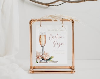 May include: A white sign with the text "FULLY EDITABLE Custom Sign" in a pink script font. The sign features a watercolor illustration of a champagne flute, magnolia flowers, and pearls. The sign is displayed in a copper pipe frame.