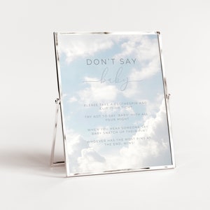 Puede incluir: Un cartel enmarcado en blanco con un fondo de cielo azul y nubes blancas. El cartel dice "No digas bebé" y tiene instrucciones para un juego. Las instrucciones dicen que tomes una pinza de la ropa y la sujetes bien apretada, intenta no decir "bebé" con todas tus fuerzas, cuando escuches a alguien decir "bebé" toma su pinza, quien tenga más pinzas al final gana!