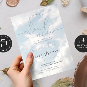 Op de afbeelding: Printbare bruiloft douche uitnodiging met een blauwe lucht en witte wolken achtergrond. De tekst luidt: "De bruid is op wolken. Doe mee met ons voor een bruiloft douche ter ere van Vivianne Porter. Za | 16 | Mar. Er zal een viering zijn in Sweet Dreams Cafe, 123 Sunny Skies Way, Uw stad. Reageer alstublieft bij Monica op 123-456-7890 voor 8 maart."