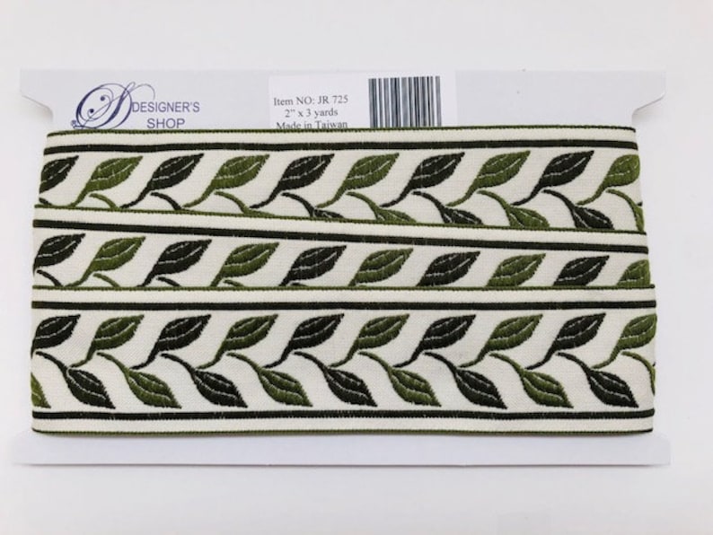 May include: A roll of decorative trim featuring a repeating leaf pattern in shades of green and black on a cream background. The trim is 2 inches wide and 3 yards long. The label reads "DESIGNER'S SHOP".