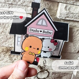Puede incluir: Un llavero con un dise&ntilde;o de casa con dos personajes de dibujos animados, uno naranja y otro blanco, con el texto "Dudu &hearts; Bubu". El llavero est&aacute; hecho de acr&iacute;lico de 3 mm e incluye el texto "Best Gift for Her | Him".