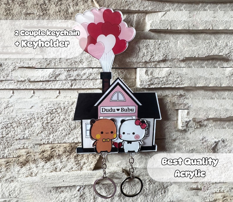 Puede incluir: Un juego de llaveros decorativos de acr&iacute;lico con un dise&ntilde;o de casa, dos personajes de dibujos animados y un grupo de globos en forma de coraz&oacute;n. El juego incluye dos llaveros y un llavero. El texto "Dudu Bubu" es visible.