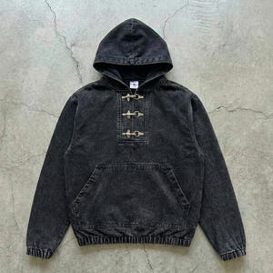 May include: A black hooded sweatshirt with a front pocket and toggle closures. The garment has a washed, faded appearance. The hood is attached, and the cuffs and hem are ribbed. The sweatshirt is made of a soft material.