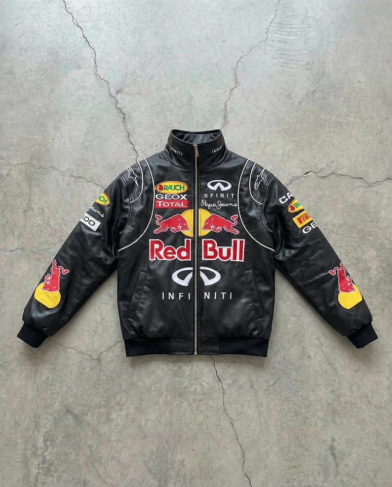 May include: Black leather jacket with a stand-up collar and a full-length zipper. The jacket features multiple sponsor logos, the Red Bull logo, and the Infiniti logo. White piping accents the design.