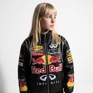 May include: Black Red Bull racing jacket with multiple sponsor logos, including Infiniti and Pepe Jeans. The jacket features a full-zip closure, white accents, and a Red Bull logo on the front. The jacket is a sporty style.