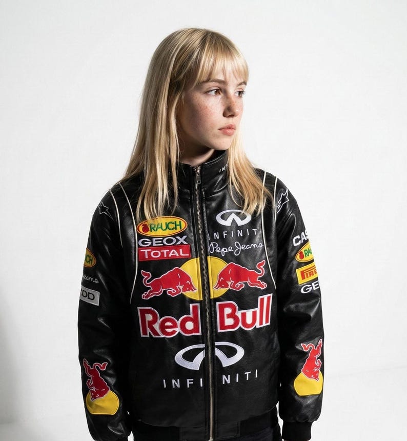 May include: Black Red Bull racing jacket with multiple sponsor logos, including Infiniti and Pepe Jeans. The jacket features a full-zip closure, white accents, and a Red Bull logo on the front. The jacket is a sporty style.